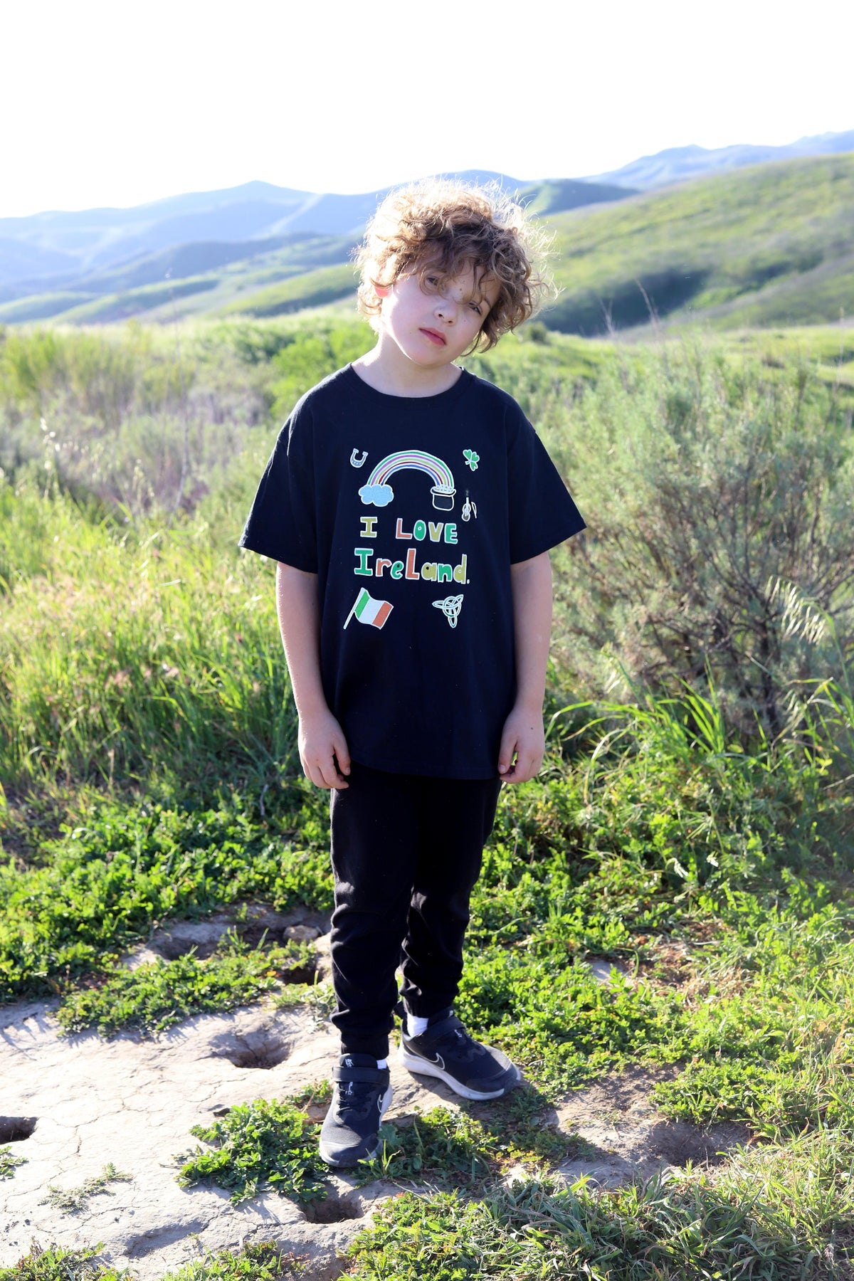 Child wearing a black t-shirt with colorful graphics and text, standing in a Ireland For St. Patricks Day